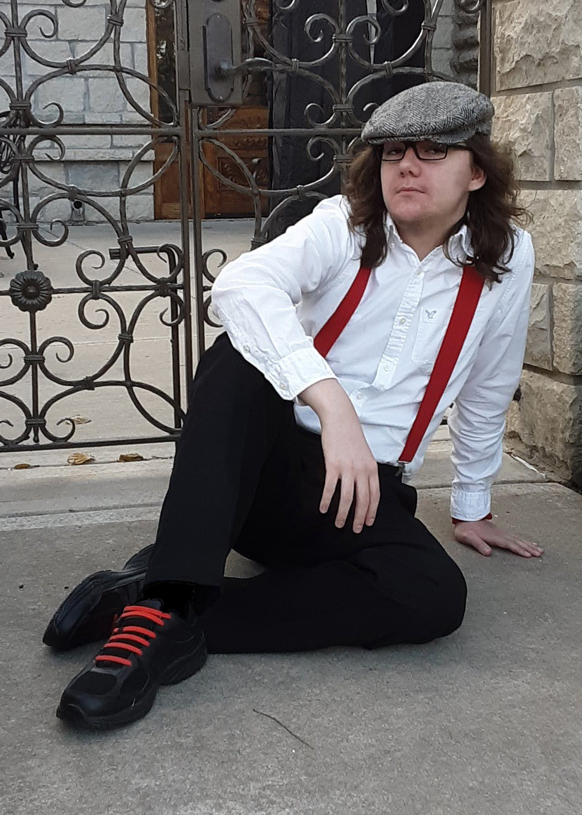 Picture of Jeremy Meyers dressed in a cap, white shirt with red suspenders, black pants, and black shoes with red laces.